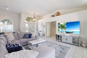 A modern living room with a large flat-screen TV, a grey sofa, and a patterned rug. - Walk to Beach! Family Retreat! (Marco Island)