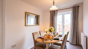 Un coin repas avec une table ronde, quatre chaises, un vase de fleurs et des aliments pour le petit-déjeuner.