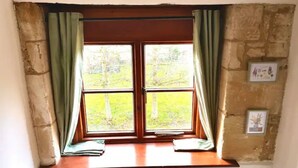 A window with two panes, curtains, and a wooden ledge. - Converted 17th century barn with garden parking - Pass the Keys (Cheltenham)