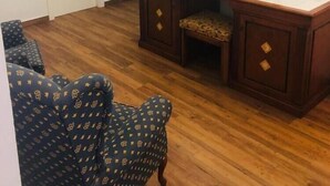 Una habitación con un escritorio de madera, una silla, un espejo y una puerta.