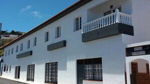 Un edificio blanco con tejado de tejas, un balcón con balaustradas blancas y un cartel que dice "HOTEL BOOMERANG".