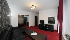 A modern living room with a red carpet, a black sofa, a wooden coffee table, a TV on a black stand, and a door leading to another room. - Hotel Rebis International (Chiscani)