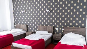 A hotel room with three single beds, each with a wooden headboard and red bedding. The room has a patterned wallpaper and a red carpet. - Hotel Rebis International (Chiscani)