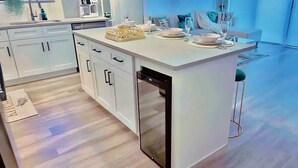 A modern kitchen with white cabinetry, a dishwasher, and a dining area with a table set for two.