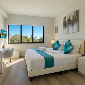 Una habitación de hotel moderna con un ventanal grande, una cama con almohadas color turquesa, un escritorio y una mesita de noche.