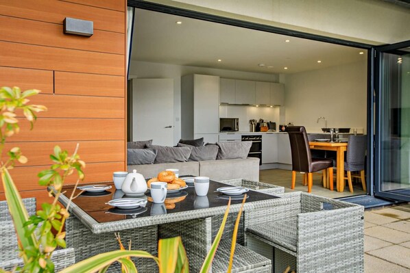 Un espace de vie moderne avec une table à manger dressée pour le petit-déjeuner, un canapé et une cuisine en arrière-plan.