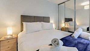 A hotel room with a bed, a nightstand, a mirror, and a towel. - 2 Bed in Woolacombe (oc-b27396) (Woolacombe)