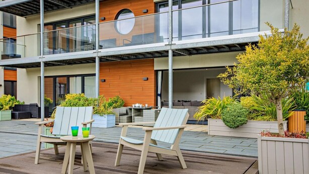 A modern outdoor seating area with two Adirondack chairs, a small table, and potted plants. - 2 Bed in Woolacombe (oc-b27396) (Woolacombe)