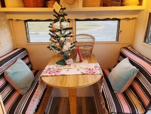 Relax in a cozy seating area with a round table and cushioned benches, featuring a window with a view of the outdoors.