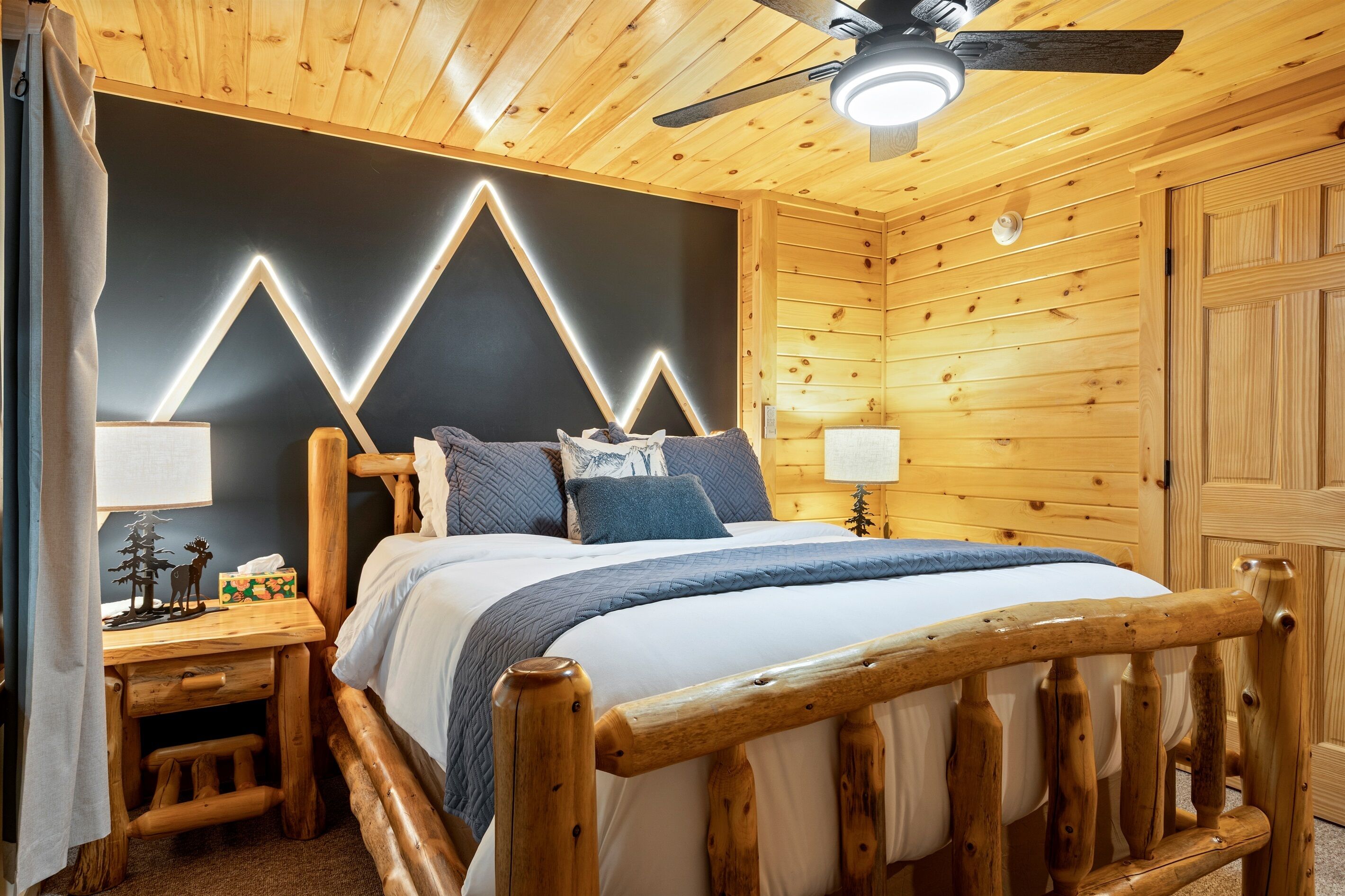 A wooden cabin-style bedroom with a bed, nightstands, and a ceiling fan.