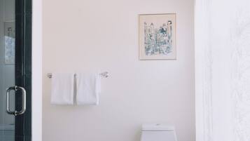 A bathroom with a toilet, a framed picture on the wall, and a glass shower enclosure.