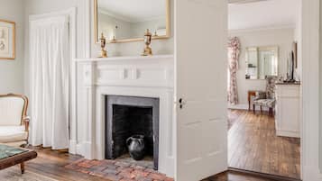 A room with a white fireplace, a mirror above it, and a door leading to another room.