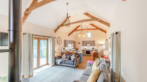 Een ruime woonkamer met een open haard, een bank en een keuken op de achtergrond.