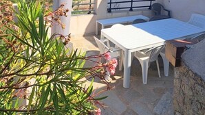 An outdoor patio with a table and chairs, a white pillar, and a view of the sea. - Villa Tarco, sleeping facilities, directly on the beach, 300 m from the beach (Conca)