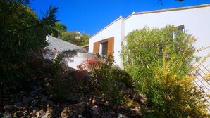 A white building with a wooden door and a stone pathway leading to it. - Villa Tarco, sleeping facilities, directly on the beach, 300 m from the beach (Conca)