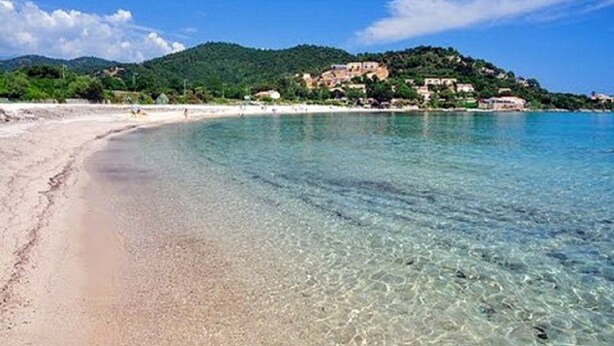 A beach with clear water, a sandy shore, and buildings on a hillside in the background. - Villa Tarco, sleeping facilities, directly on the beach, 300 m from the beach (Conca)