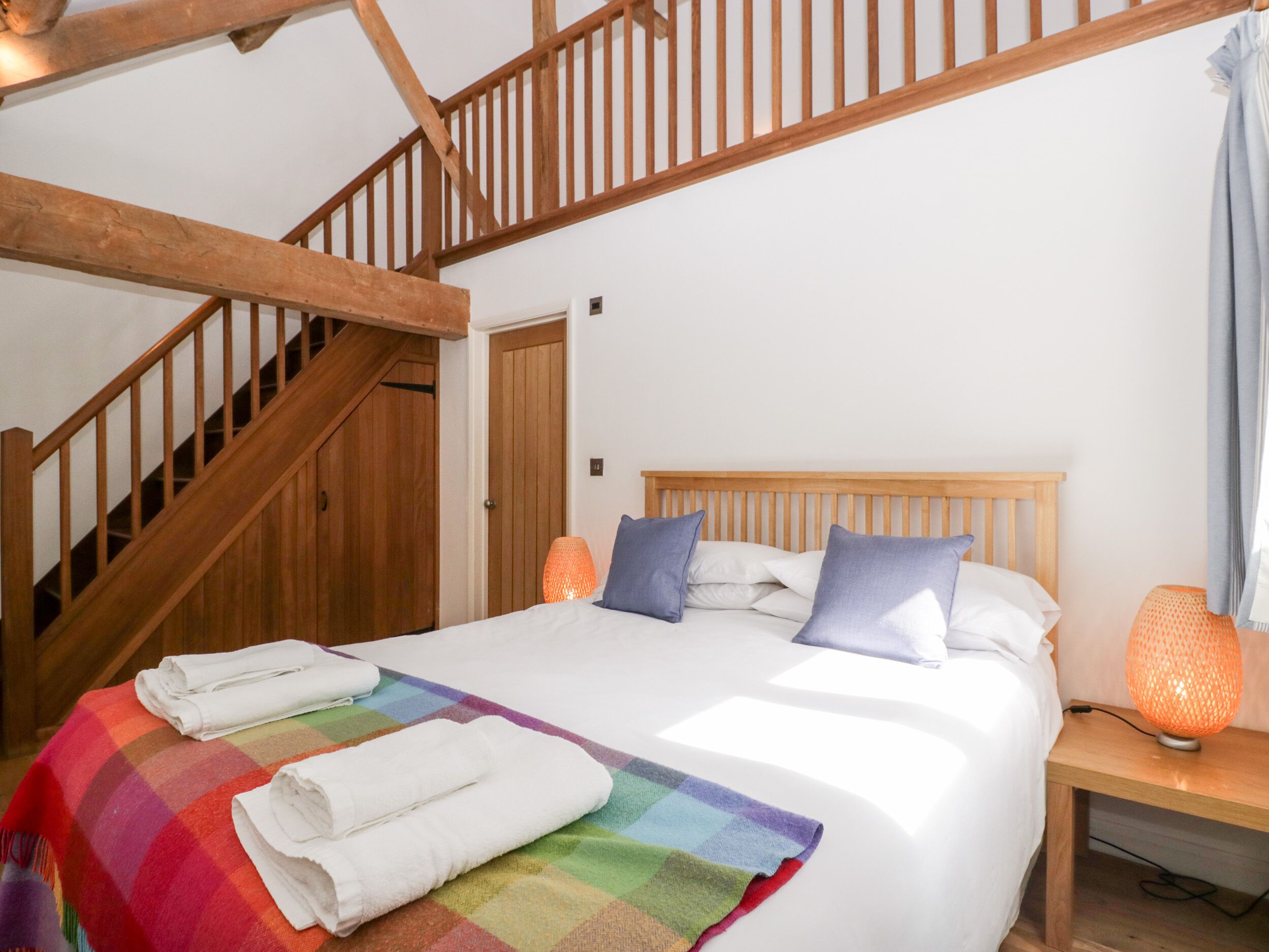 Un dormitorio con una cama de madera, un edredón colorido y una mesita de noche con una lámpara.