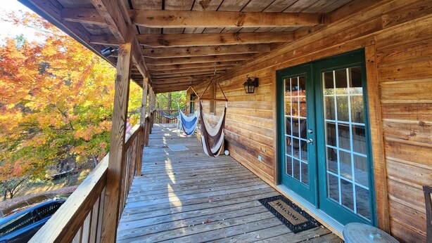 Eine Holzhütte mit Veranda, einer Hängematte und Blick auf Herbstlaub.