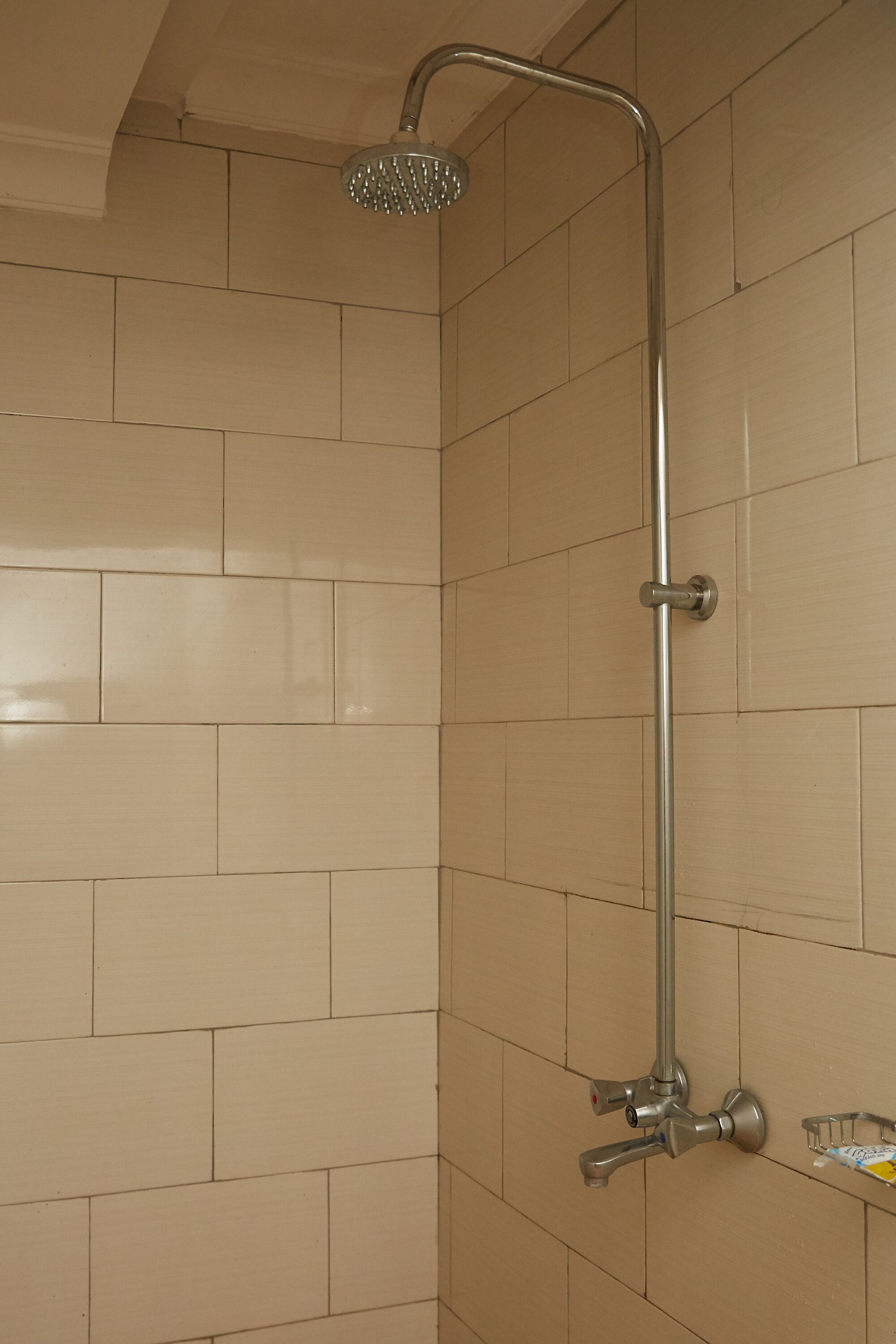 A shower with a handheld showerhead and a wall-mounted faucet.