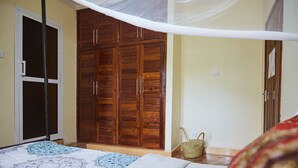 Un dormitorio con cama, armario de madera y mosquitero.