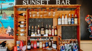 Un bar llamado "Sunset Bar" con una variedad de botellas y vasos exhibidos en estantes.