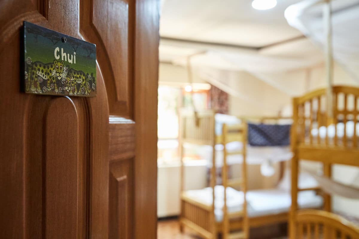 A wooden door with a sign reading "Chui" and a room with wooden furniture and a bunk bed in the background.