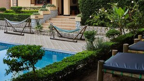 Un edificio de varios pisos con piscina, mobiliario exterior y jardines bien cuidados.