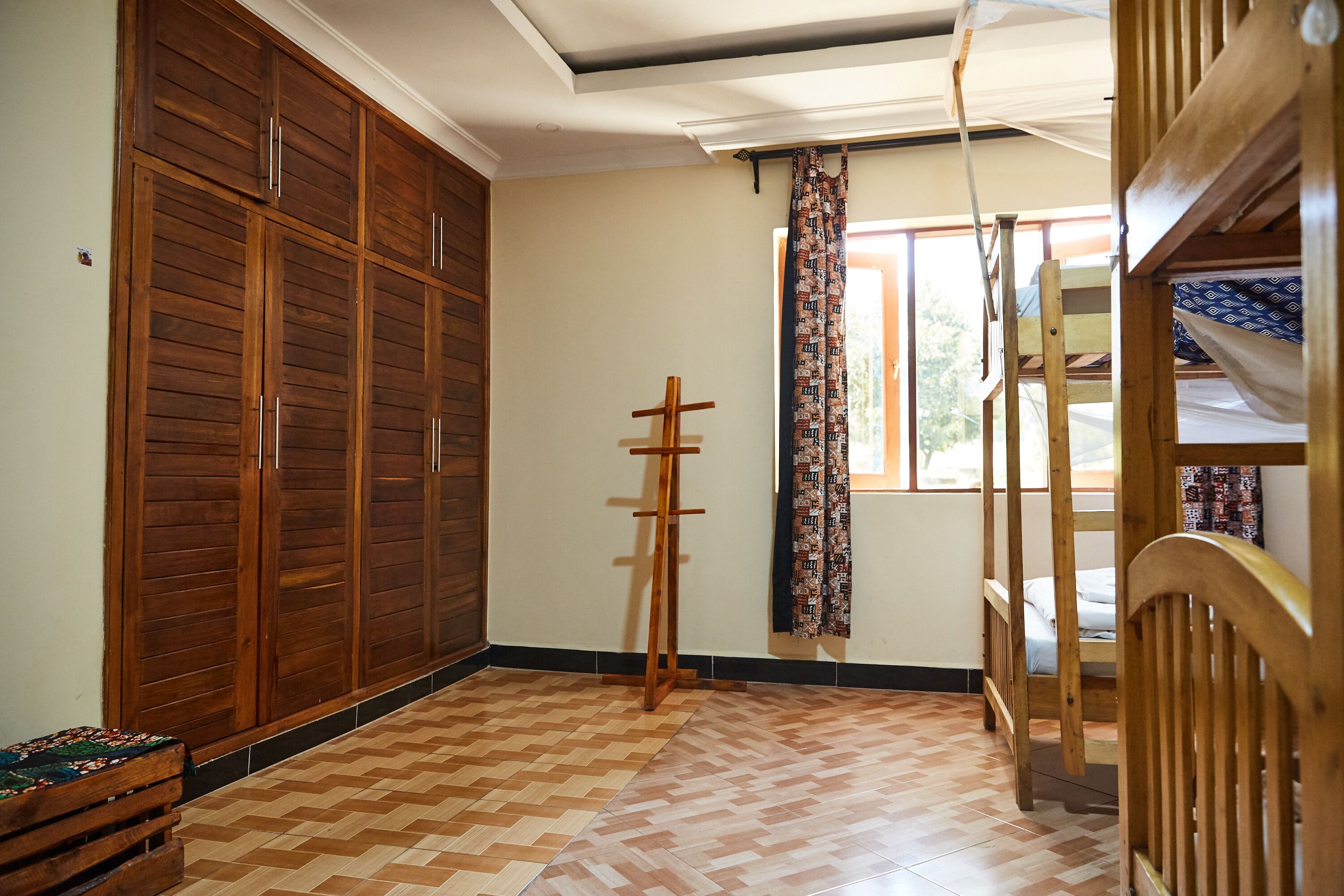 A room with a large wooden wardrobe, a wooden ladder, and a patterned curtain.