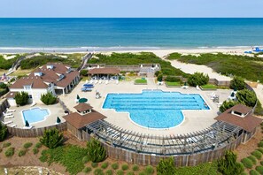 Een resort met een groot zwembad, toegang tot het strand en meerdere gebouwen.