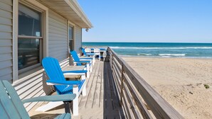 A wooden deck with blue chairs and tables overlooking a beach. - Torchsong: Oceanfront, Direct Beach Access, Dogs OK (Nags Head)
