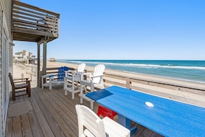 Une terrasse en bois avec une table et des chaises donnant sur une plage.