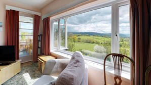 A living room with a large window, a television, a sofa, and a wooden chair. - Eryl - Three Bedroom Cottage, Sleeps 5 (Rowen)