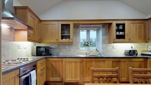 A kitchen with wooden cabinets, a microwave, a stove, and a window with a view.