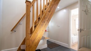 A wooden staircase leading to a bathroom with a white door and a towel hanging on it. - The Barn - One Bedroom Cottage, Sleeps 2 (Bala)