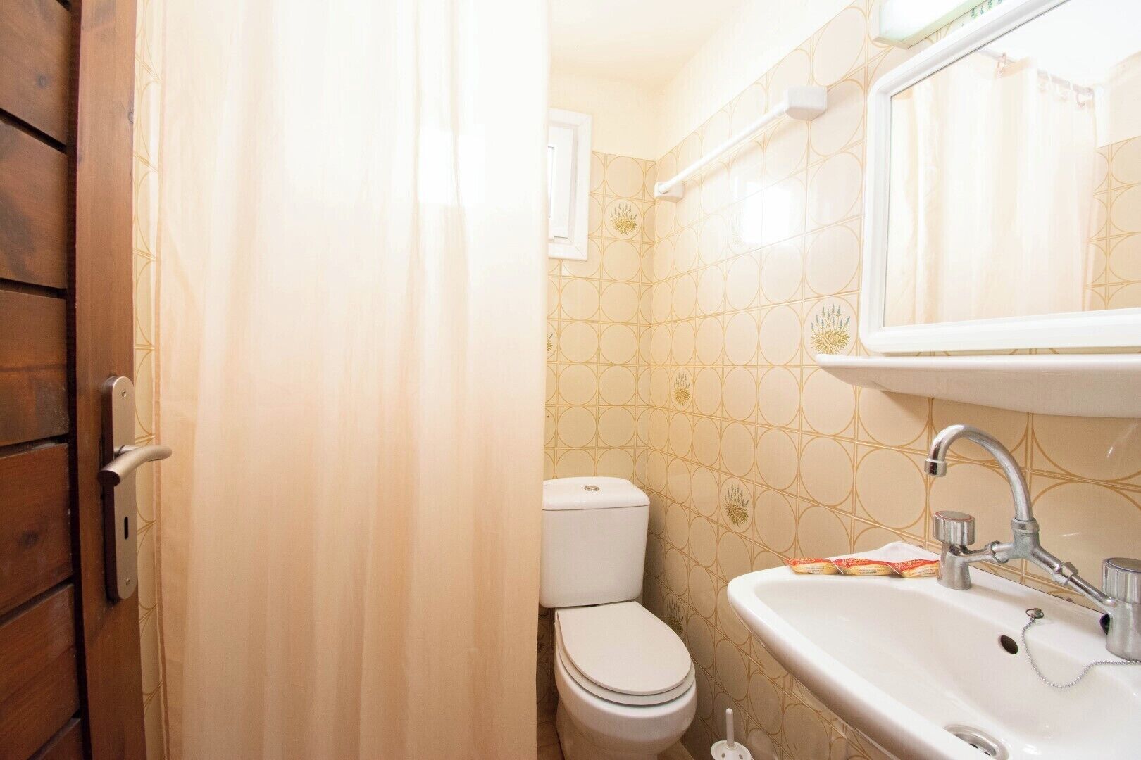 Une salle de bain équipée de toilettes, d’un lavabo et d’un rideau de douche.