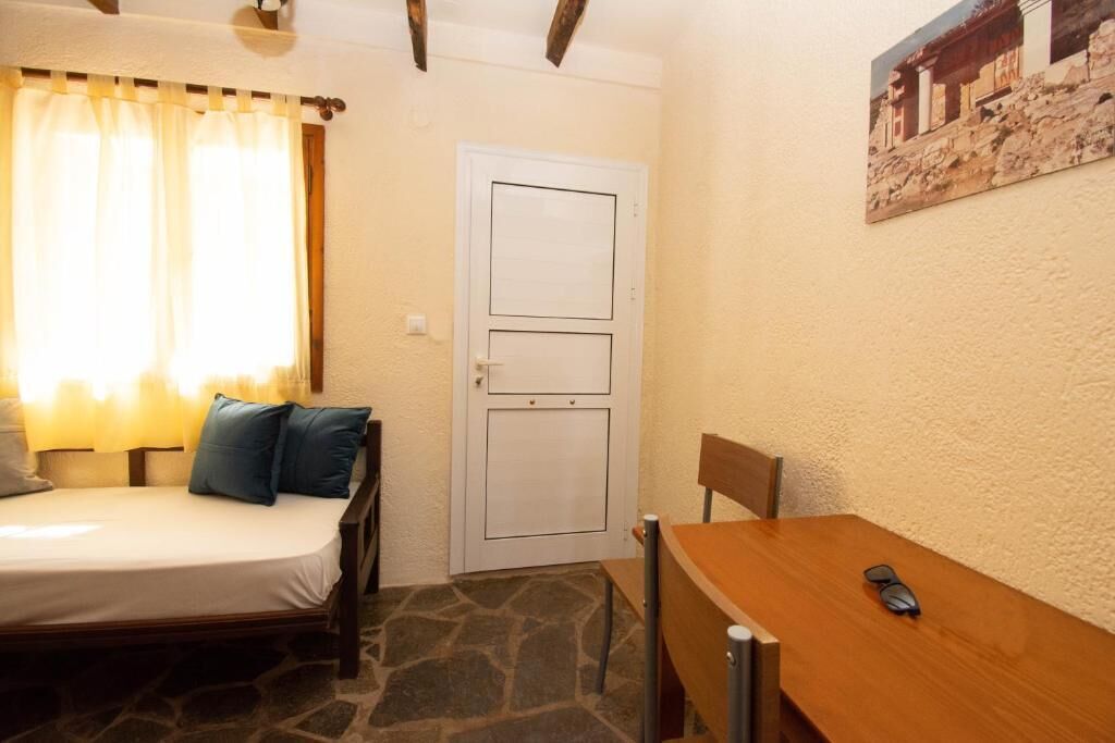 A small room with a bed, a wooden table, and a door.