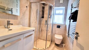 Une salle de bain moderne avec une douche à parois incurvées, un lavabo blanc et des toilettes.