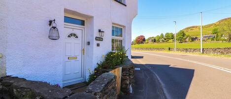 A white building with a stone wall entrance, a door, and a window.