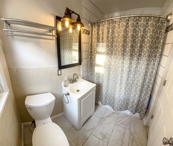 Un baño con inodoro, lavamanos y cortina de ducha.