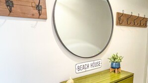 Ein Zimmer mit einem grünen Schminktisch, einem runden Spiegel und einem Schild mit der Aufschrift 'BEACH HOUSE'.