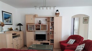 Ett vardagsrum med en röd soffa, en tv och en bokhylla.