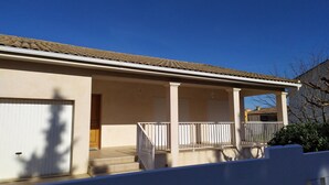 Ett tvåvåningshus med en inglasad veranda, ett garage och en synlig trappa som leder upp till övre våningen.
