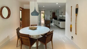 Een moderne eetruimte met een ronde tafel en stoelen, een hanglamp en uitzicht op de keuken.