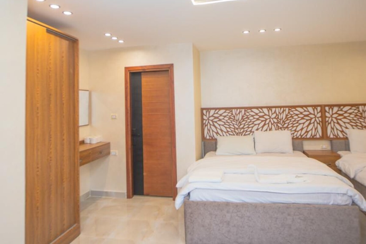 A bedroom with a bed, a wooden wardrobe, and a door.