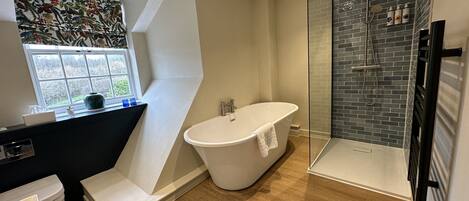 A modern bathroom with a freestanding bathtub, a glass-enclosed shower, and a window with a view.