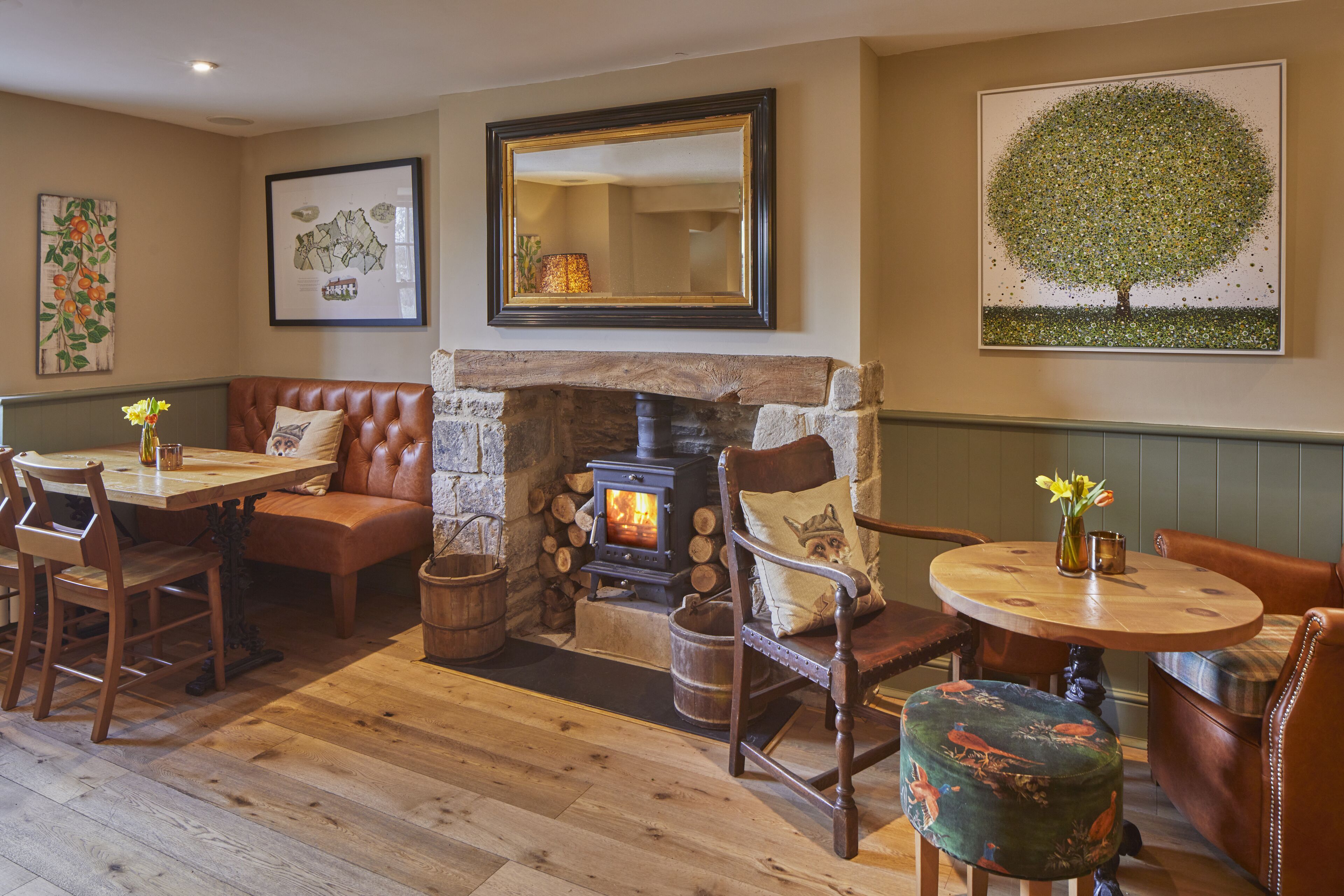 A cozy room with a stone fireplace, leather furniture, and artwork on the walls.