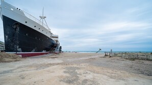 Un grand navire était amarré sur une plage de sable, sous un ciel dégagé.
