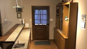 A compact kitchen with a wooden countertop, a sink, a window with a curtain, and a ceiling light fixture. - Stuttgart Lodge (Stuttgart)