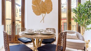 A dining area with a round table, chairs, and a large decorative leaf on the wall. - Genteel Home Santas Patronas II (Seville)