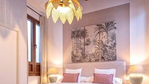 A bedroom with a bed, bedside tables, a hanging light fixture, and a wall mural. - Genteel Home Santas Patronas II (Seville)